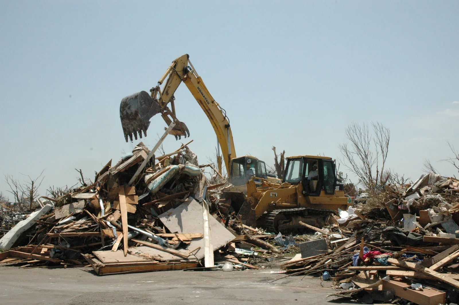 Excavator and tracked loader removing building debris