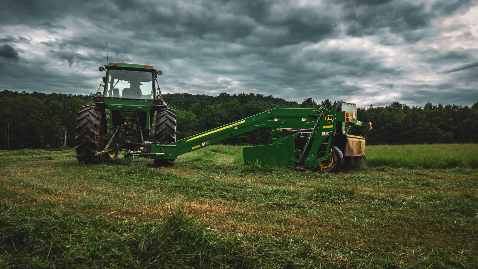 Tractor with a mower cutting a grassy field